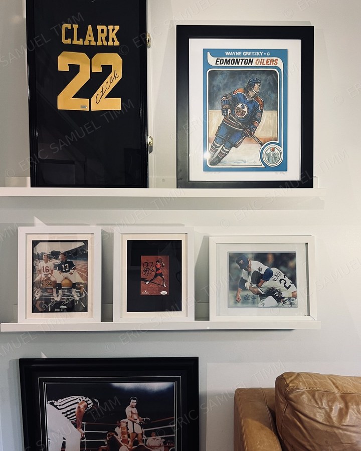 Framed Wayne Gretzky print on a picture ledge alongside a framed signed jersey and other framed memorabilia